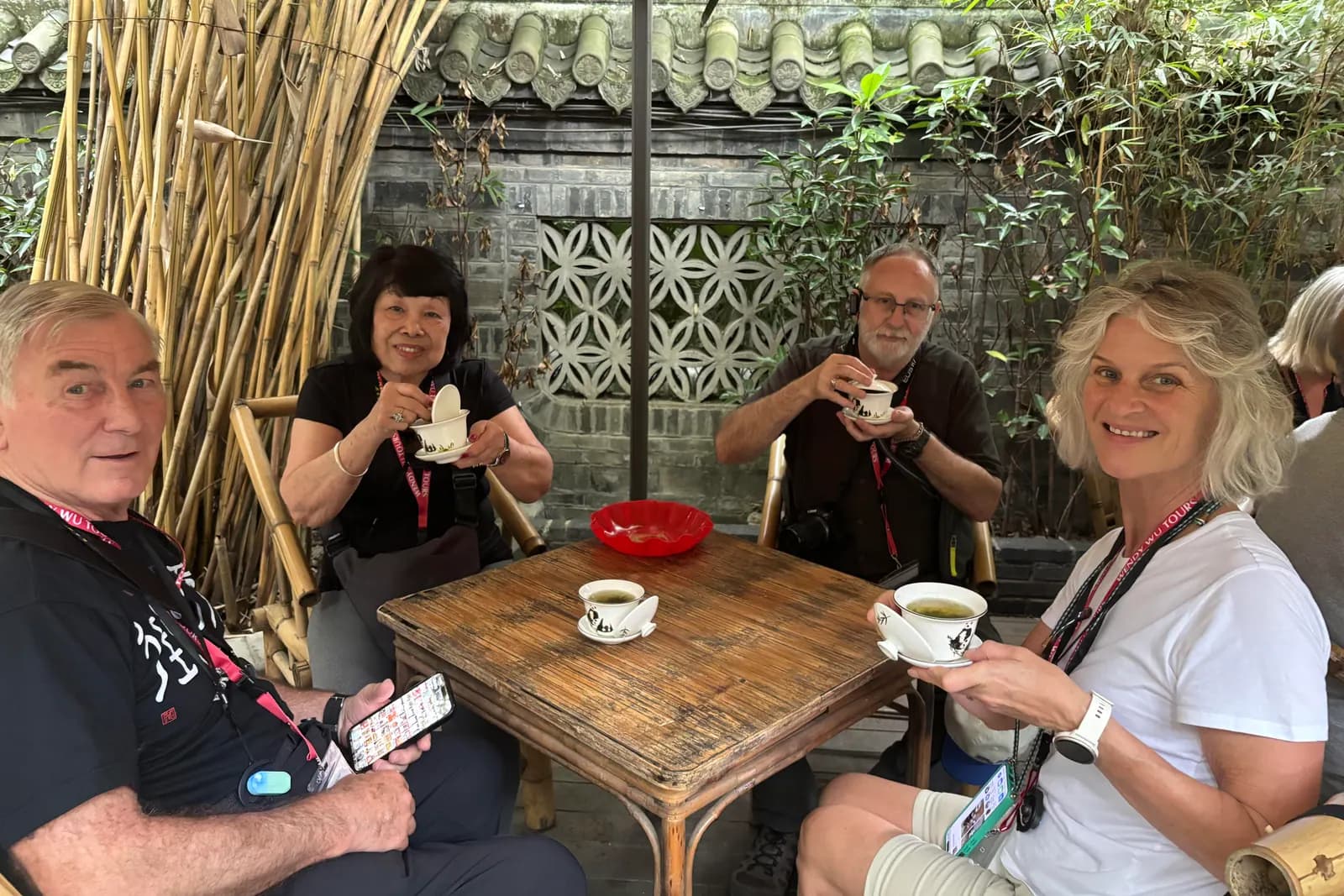 International visitors sharing covered-bowl tea with a local English-speaking guide