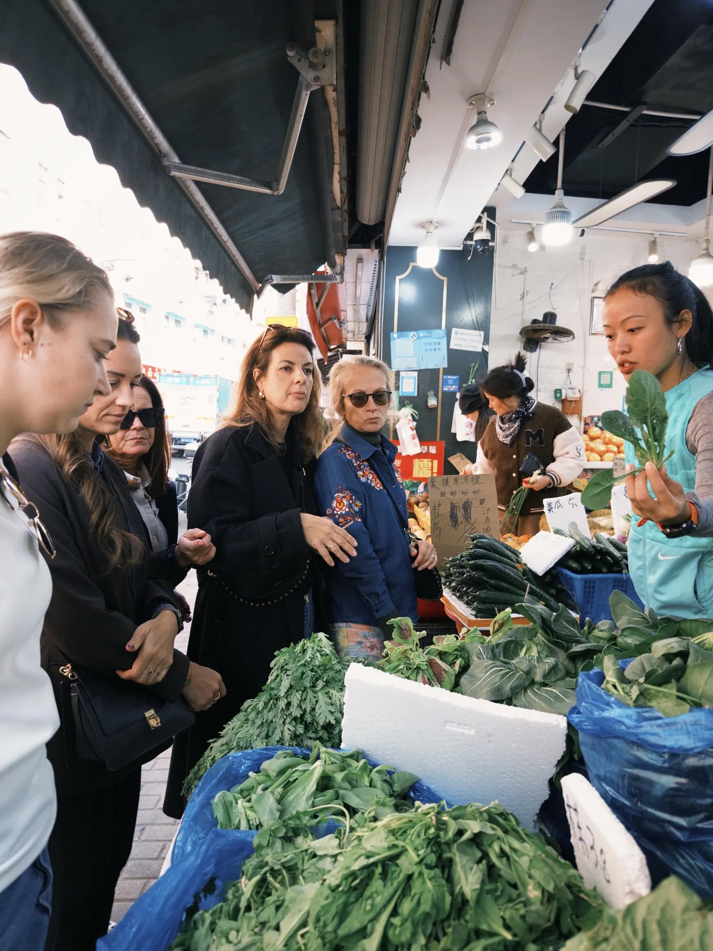 Travelers looking at fresh produce in a Shanghai neighborhood market
