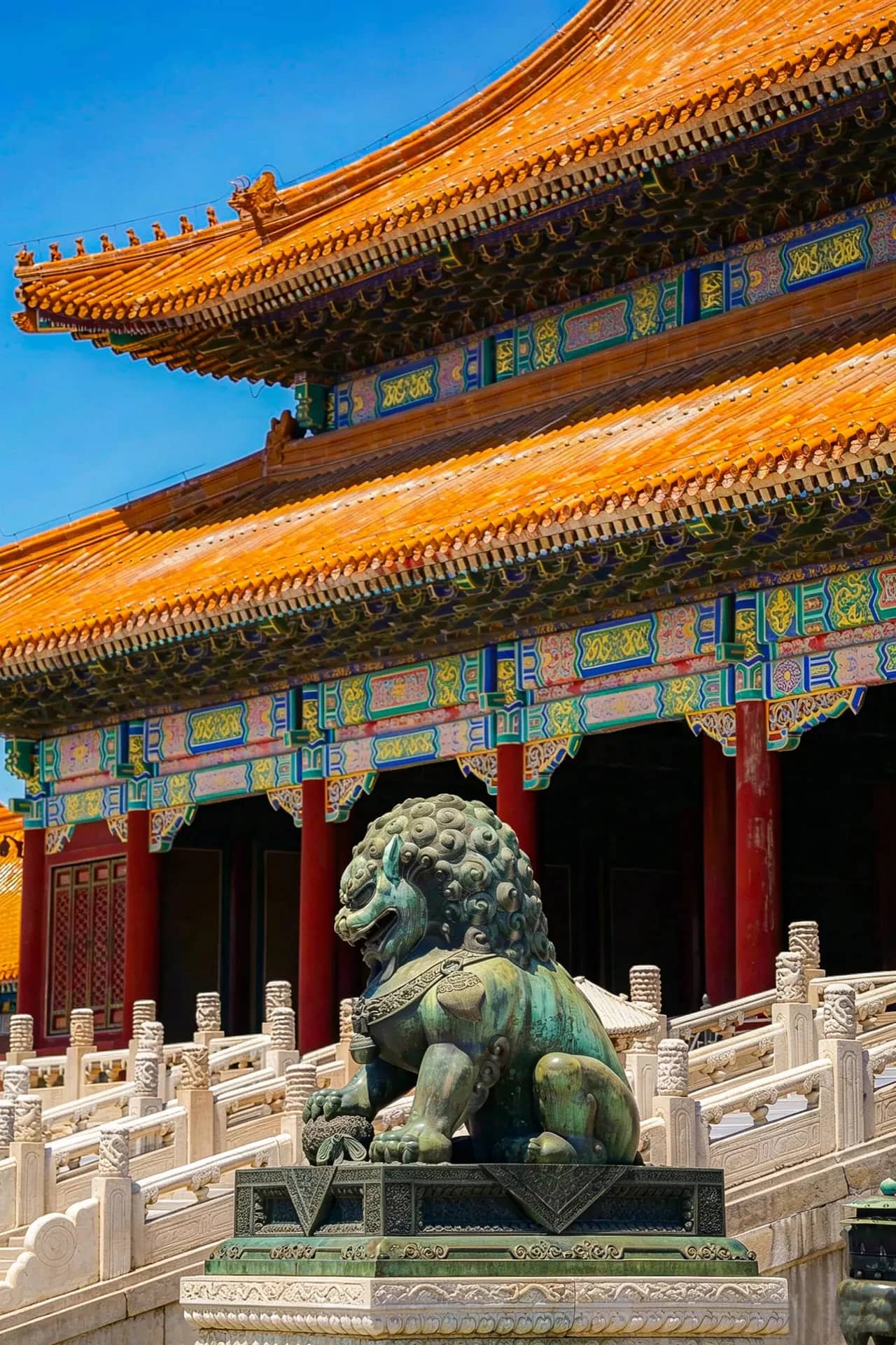 A stone lion and colorful palace roofs inside the Forbidden City in Beijing