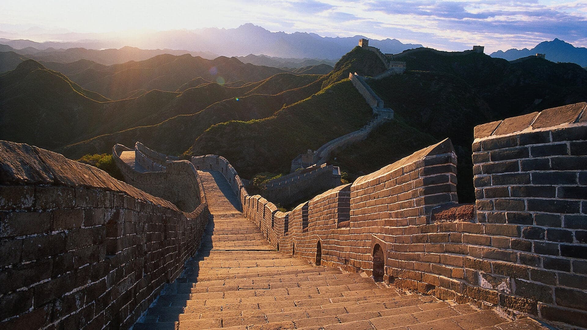 The Great Wall winding across mountain ridges near Beijing in warm evening light