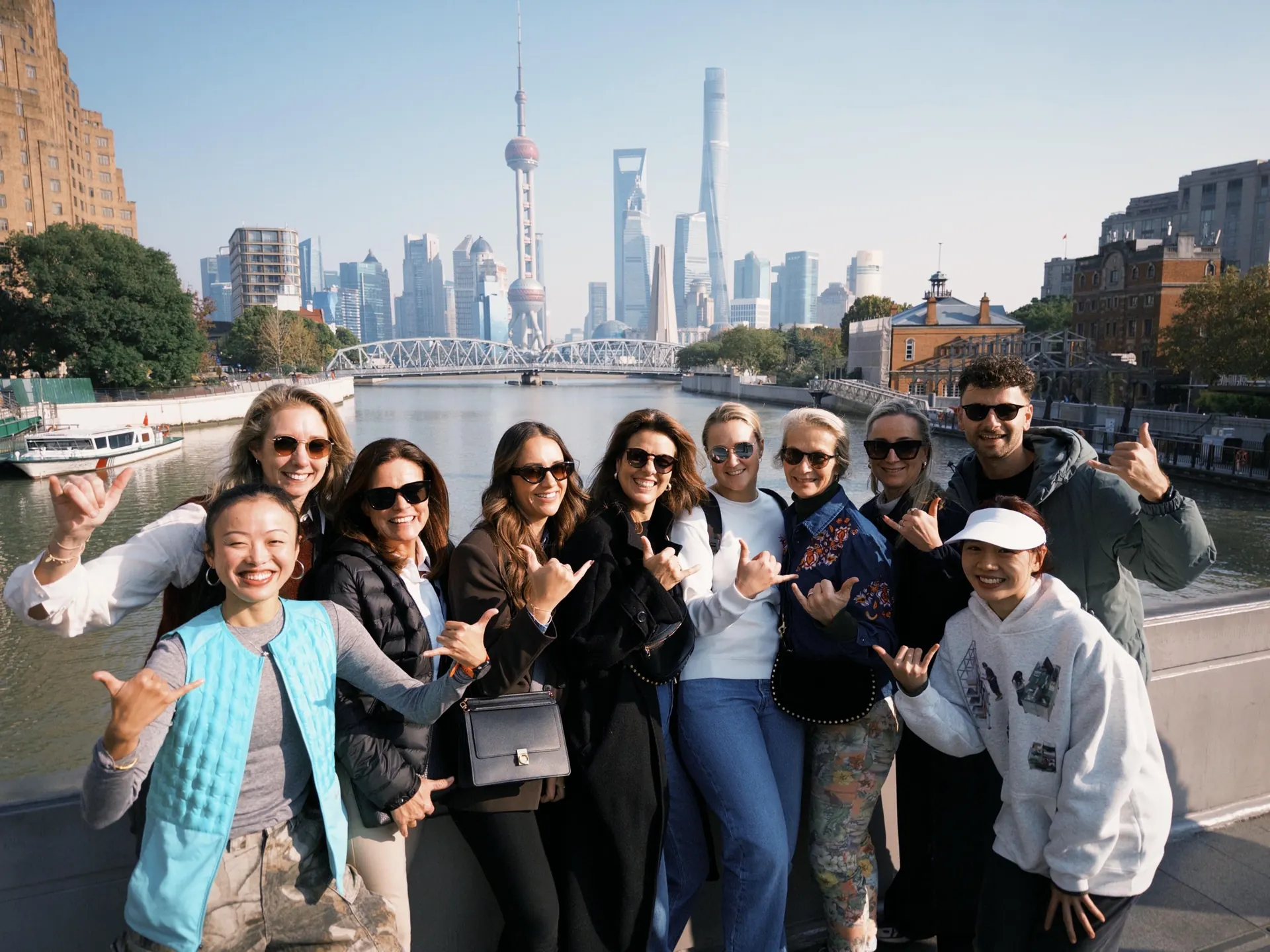Travelers gathered beside a Shanghai waterfront with the Pudong skyline behind them